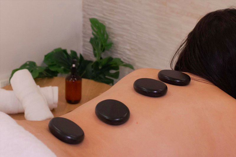 Masaje con piedras volcánicas calientes para relajación en Rituals by Glow
